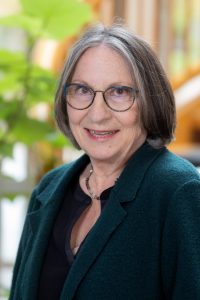 Woman in green coat, indoor setting.