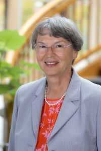 Woman in gray blazer with pearls.