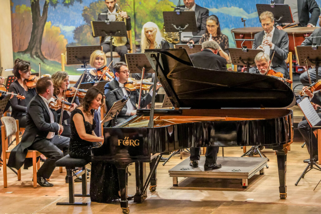 Pianist performing with orchestra on stage.